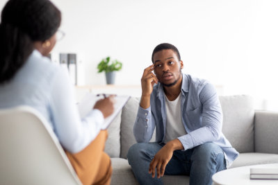 Stressed black man suffering from depression, counselor providing professional assistance